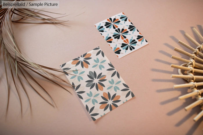 Two floral pattern cards on a beige surface with decorative dried leaves and a bamboo mat.