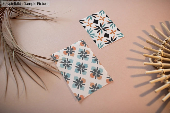 Two floral-patterned cards on a beige surface with decorative leaves and bamboo sticks.