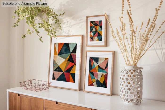 Modern living room decor with geometric art and dried plants on a wooden sideboard.