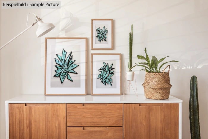 Modern wooden cabinet with framed cactus illustrations and potted plants on top.