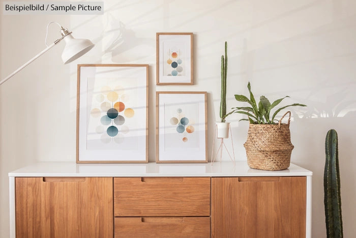 Stylish wooden sideboard with framed abstract art and potted plants in a minimalist room.