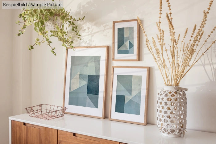 Minimalist decor with geometric art prints, a potted plant, and wicker basket on a wooden sideboard in a bright room.