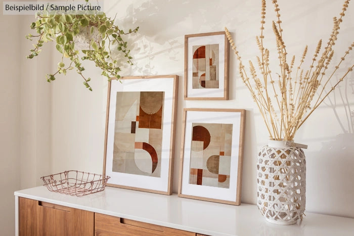 Modern geometric art in wooden frames on a wooden table with plants and a vase.