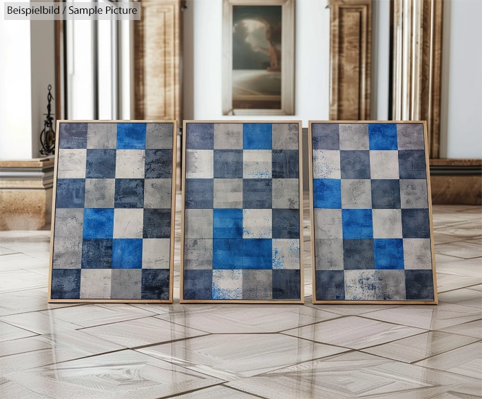 Three framed abstract paintings with blue and gray checkered patterns on a polished floor in an elegant room.