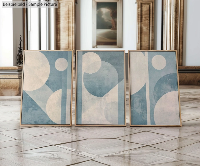 Three abstract paintings with blue and white geometric shapes displayed on a patterned floor in a gallery setting.