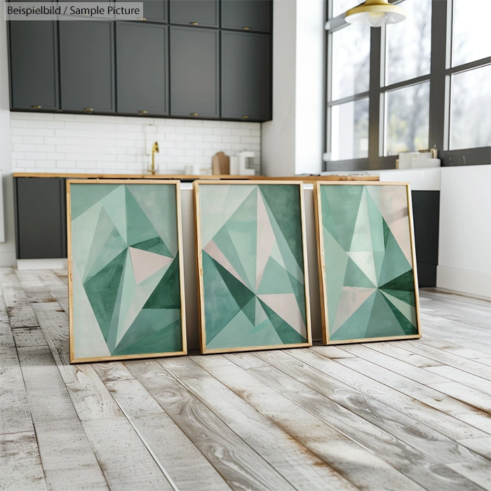 Three abstract teal and white geometric paintings in a modern kitchen with wooden floors and gray cabinets.