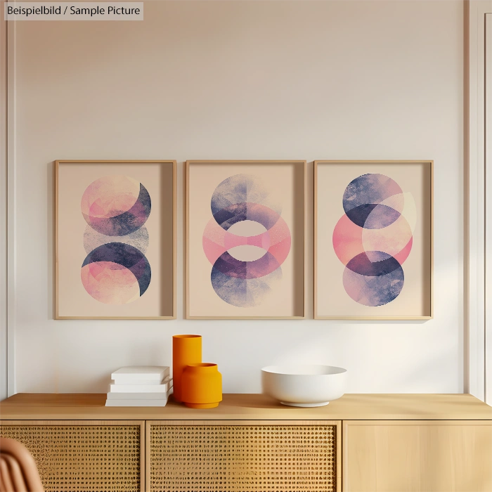 Triptych of abstract art with overlapping pink, purple, and blue circles above a wooden sideboard.