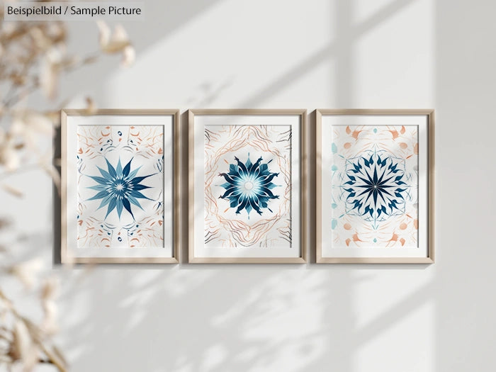 Three abstract flower art prints in frames on a wall with shadows, featuring blue and peach tones.