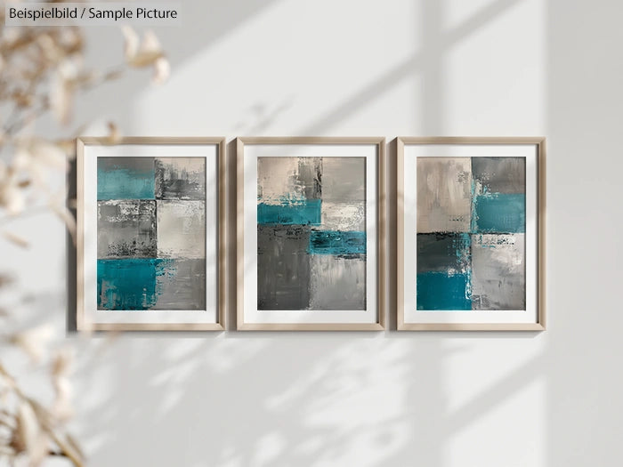 Abstract triptych with teal, gray, and beige geometric blocks in wooden frames on a light wall.