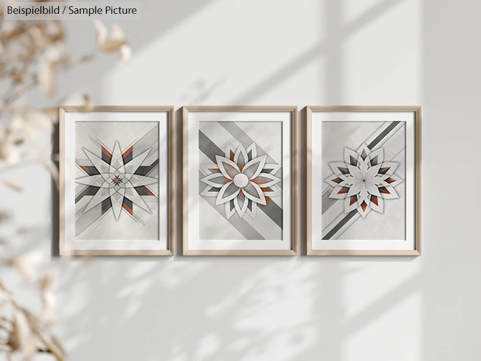 Three framed geometric floral art pieces with gray, white, and orange hues on a light-colored wall.