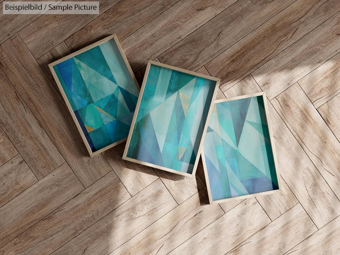 Three abstract paintings with turquoise geometric designs on wooden floor.