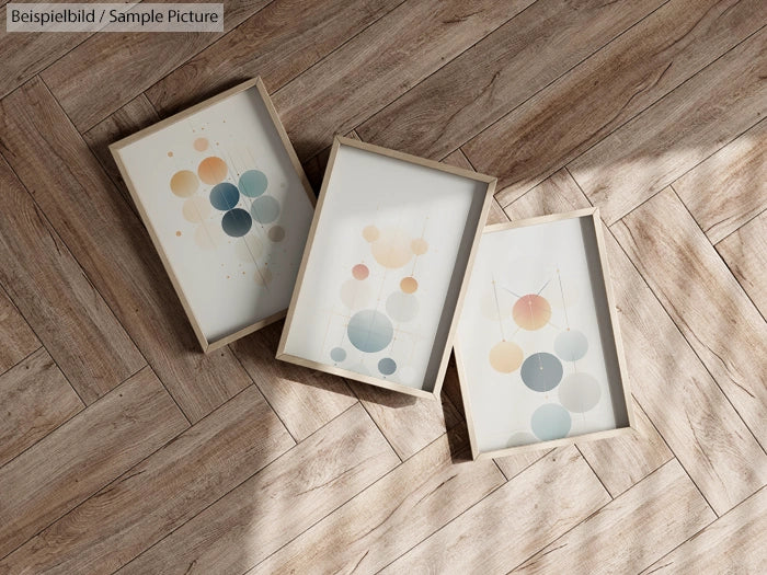 Three framed abstract art pieces with geometric circles on a wooden floor.