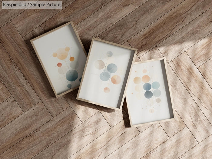 Three framed abstract geometric art prints with circles on wooden herringbone floor.