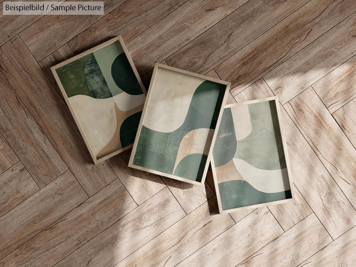 Abstract art prints with green and beige curves on wooden floor.