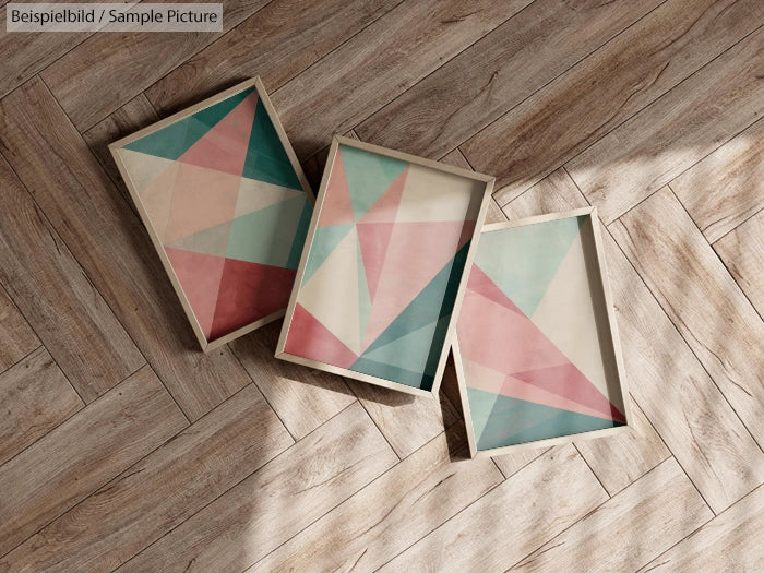 Three framed geometric art prints with pastel colors on wooden floor.