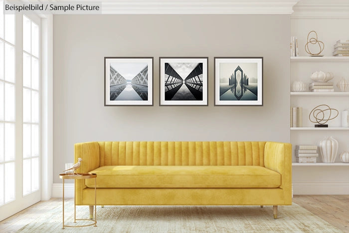 Modern living room with a yellow sofa, three geometric black-and-white prints, and decorative shelves.