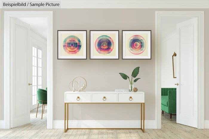 Minimalist room with three abstract circle artworks above a white console table, green chair in the background.