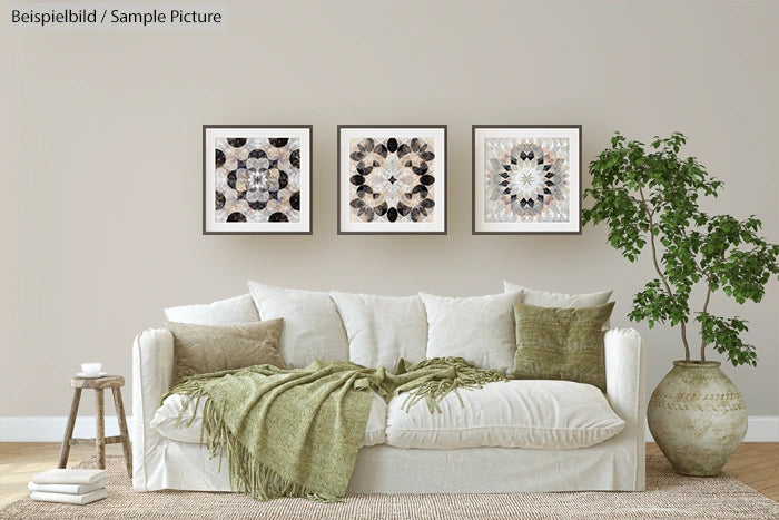 Living room with white sofa, green cushions, and three framed mandala artworks on the wall, next to a potted plant.