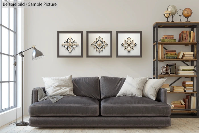 Modern living room with a gray sofa, three geometric wall art pieces, and a bookshelf filled with books and decor.