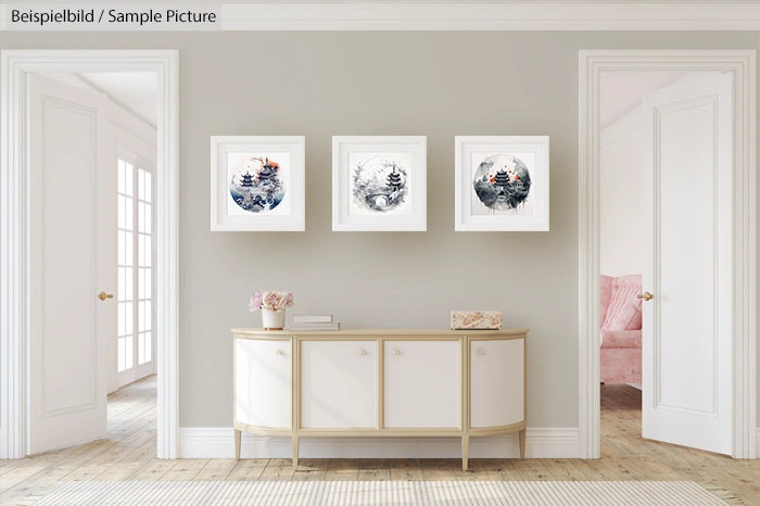 Minimalist interior with a white console table and three framed artistic prints on a light gray wall.