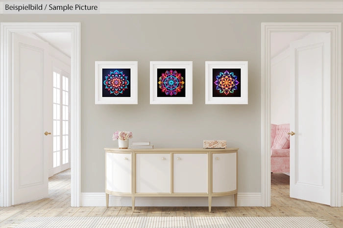 Modern living room with three colorful mandala artworks on a gray wall above a beige sideboard. Light from a window.