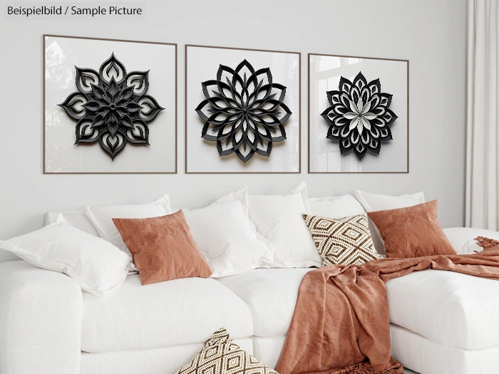 White sofa with brown cushions beneath three geometric pattern wall art pieces in a modern living room setting.