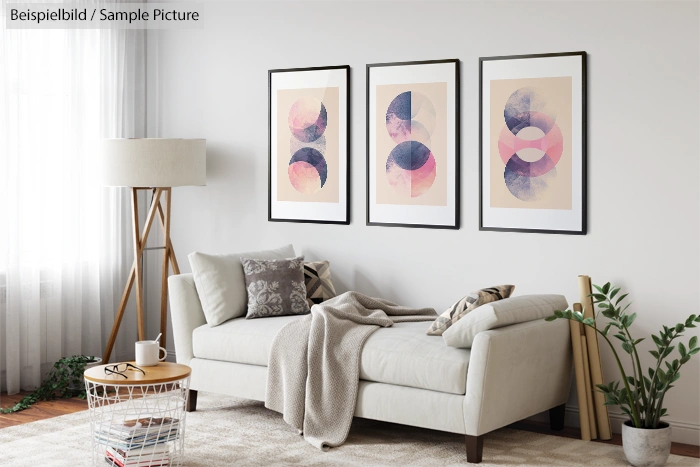 Modern living room with white sofa, floor lamp, and three abstract art prints on wall.