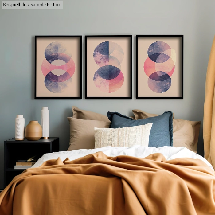 Bedroom with trio of abstract art in soft pinks and blues above bed, styled with modern pillows and decor accents.