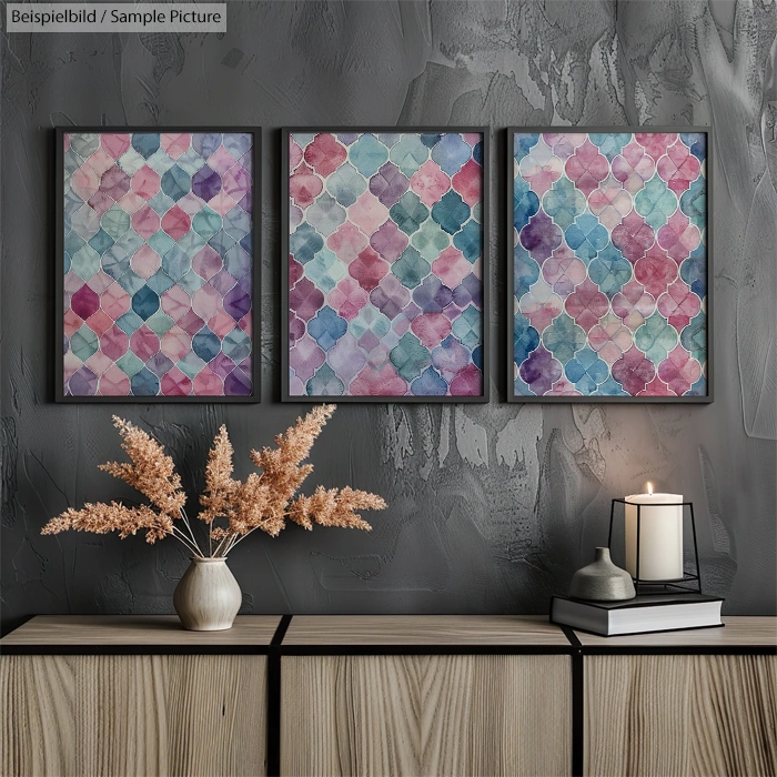 Abstract watercolor paintings with geometric patterns on a textured gray wall, decorated with a vase and candle.