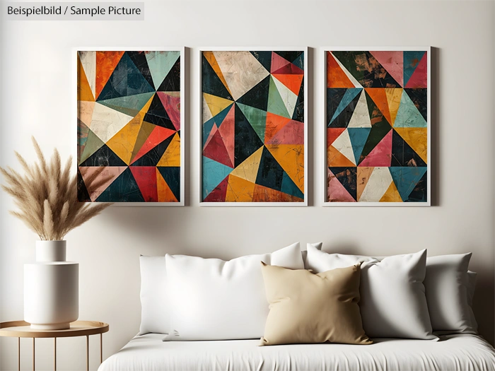 Modern living room with geometric abstract art triptych above a white couch and neutral tone pillows.