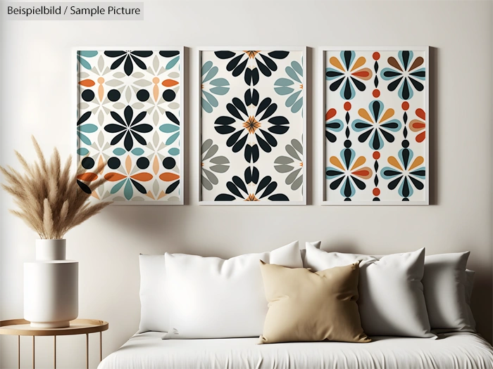 Modern living room with abstract geometric artwork on the wall, white sofa, beige pillows, and dried pampas grass in a vase.