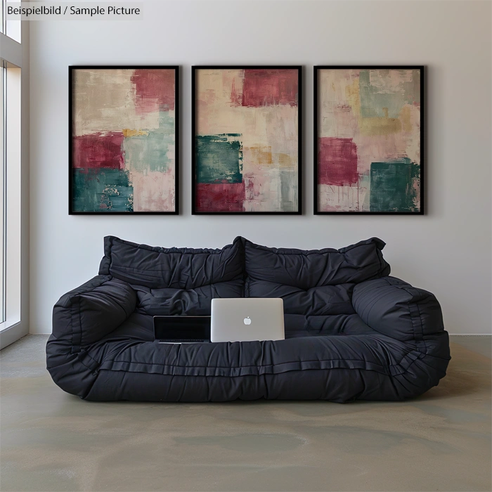 Modern living room with black couch, laptop, and abstract art on wall, featuring red, teal, and white blocks.