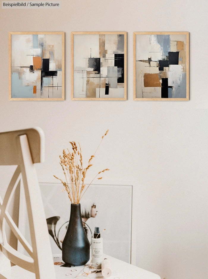 Modern abstract art on wall with beige, black, and blue tones; minimalist decor with dried flowers and a chair.