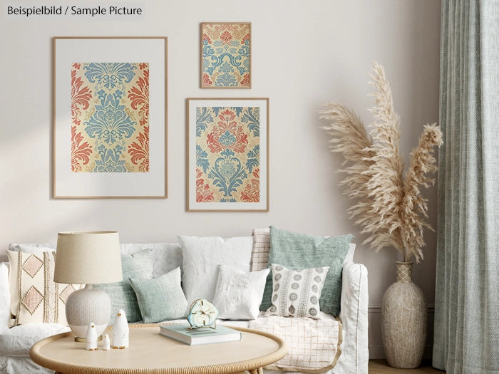 Living room with framed damask prints, beige couch, pillows, lamp, and dried plants in a vase, offering a cozy ambiance.