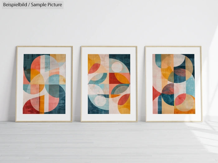 Three abstract art prints with geometric shapes in frames on a white gallery wall.