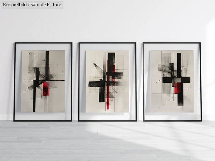 Three framed abstract paintings with black and red geometric designs displayed on a white wall.