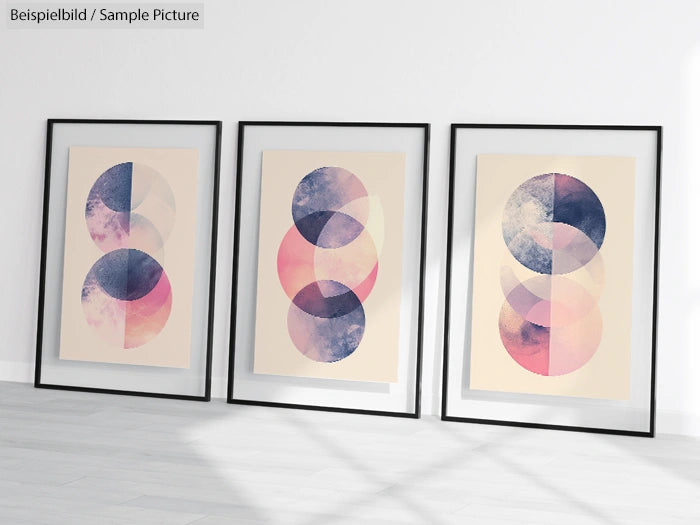 Set of three framed abstract art prints with overlapping circles in pink, blue, and purple hues on a white wall.