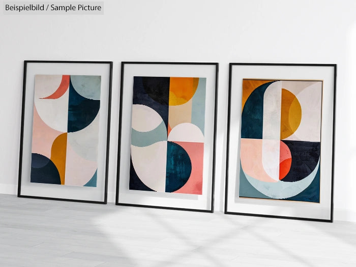 Three framed abstract paintings with geometric shapes and soft pastel colors displayed on a white wall.