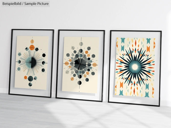 Three framed geometric artworks with circular and starburst patterns, displayed on a floor against a white wall.