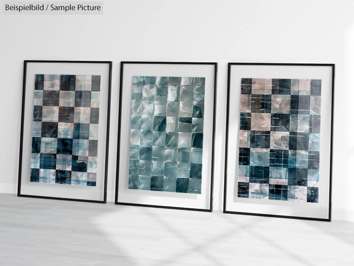 Three framed abstract artworks with blue and gray geometric patterns displayed on a white floor.