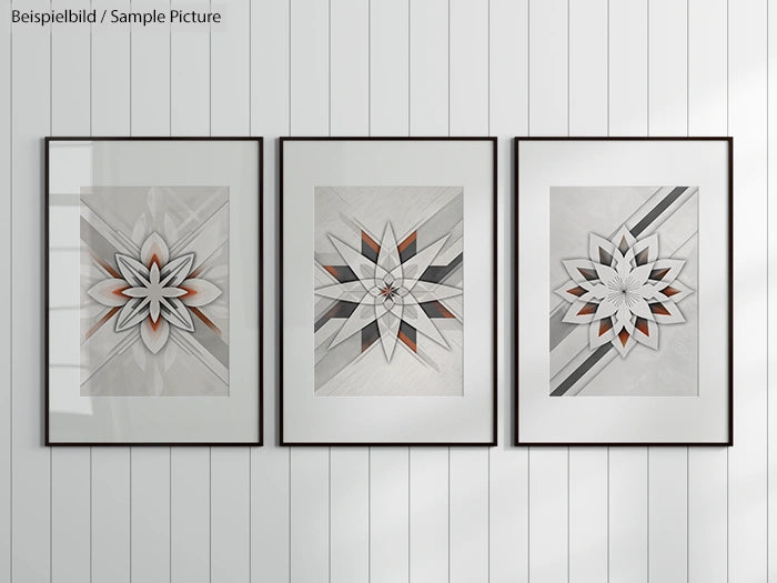 Three framed geometric artworks with star patterns on a white paneled wall, featuring shades of gray and orange.