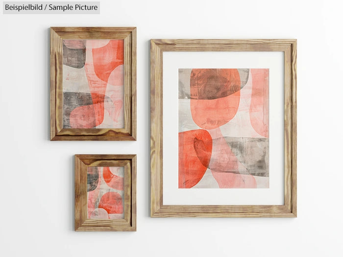 Three wooden framed abstract art pieces with red, gray, and white shapes on a white wall.