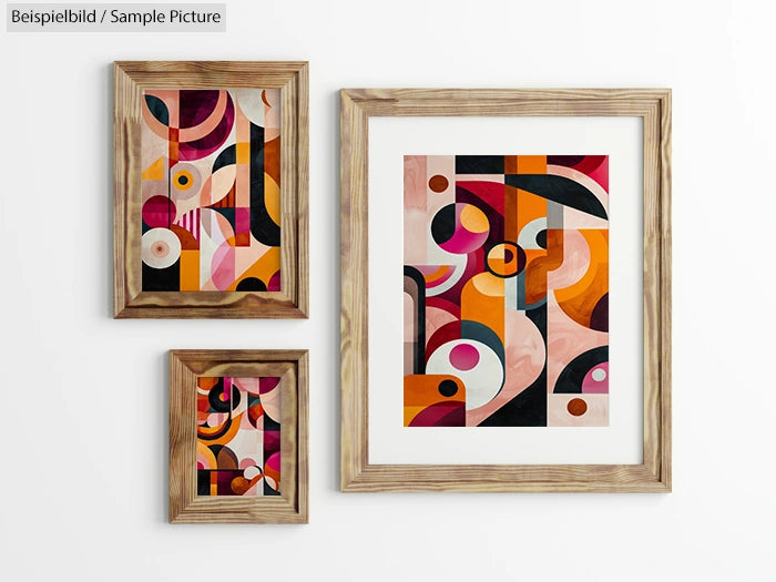 Three wooden-framed abstract art pieces with colorful geometric shapes on a white wall.