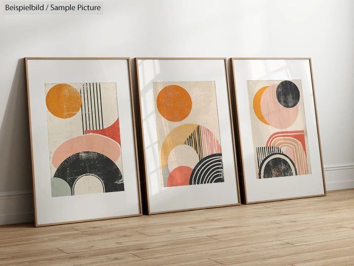 Three framed abstract geometric art prints with circles and stripes, standing on a wooden floor.