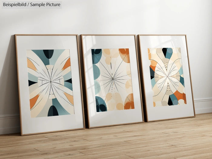 Three abstract geometric artworks in frames, featuring symmetrical patterns with pastel and earth tones, on a wooden floor.