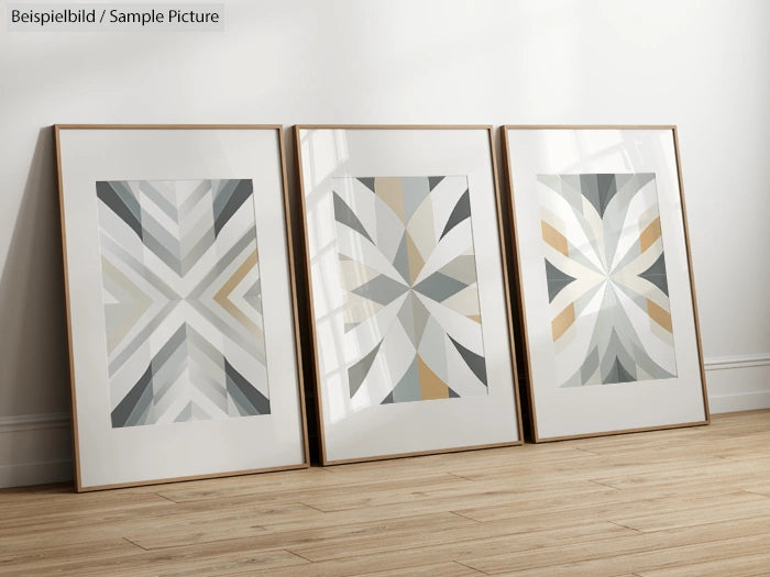 Three framed geometric abstract art pieces leaning against a wall on a wooden floor.